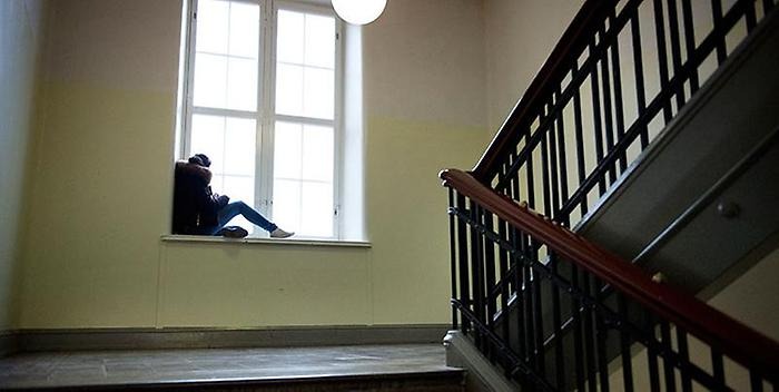 Ensam tjej sitter i ett fönster i ett trapphus