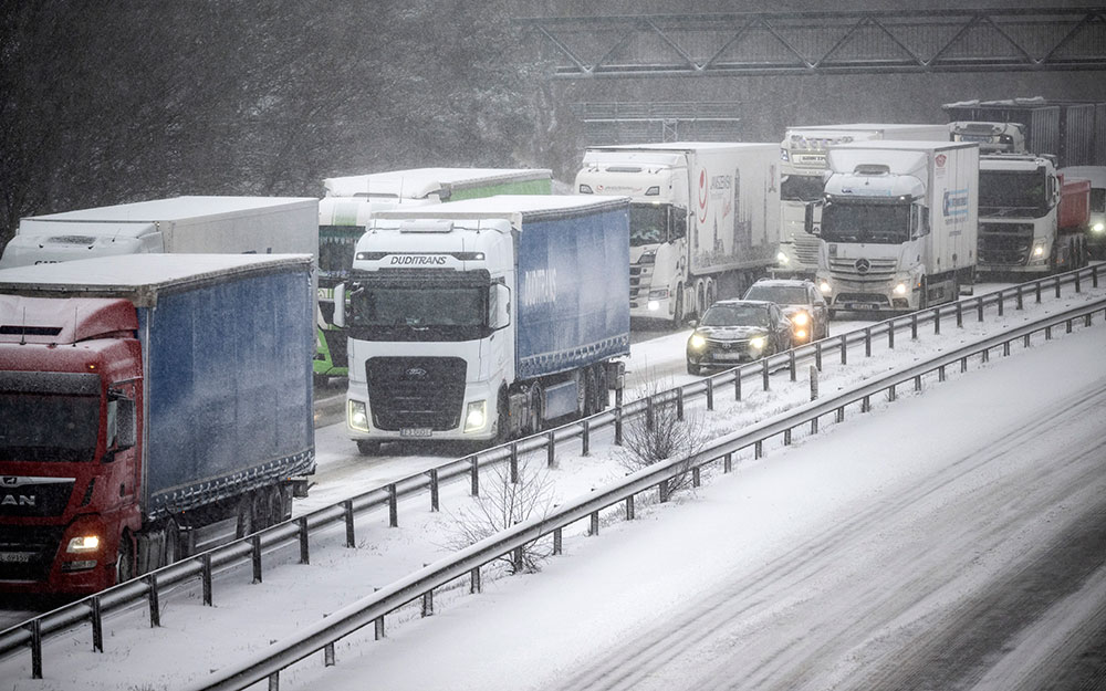 Lastbilar på rad i snöstorm